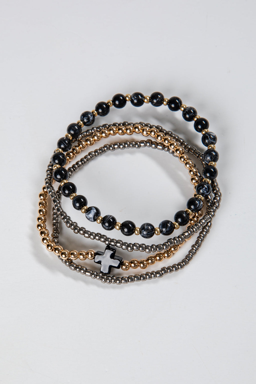 Stack of black beaded bracelets with gold and silver accents on a light gray background
