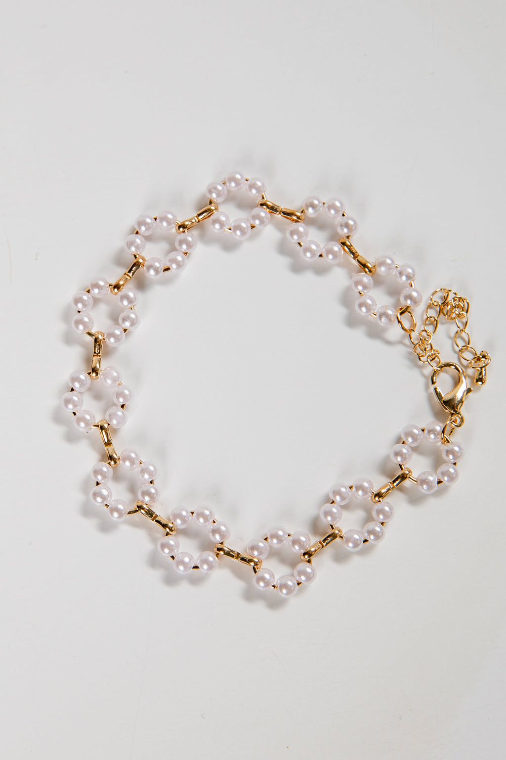 Pearl bracelet with gold chain on a light gray background