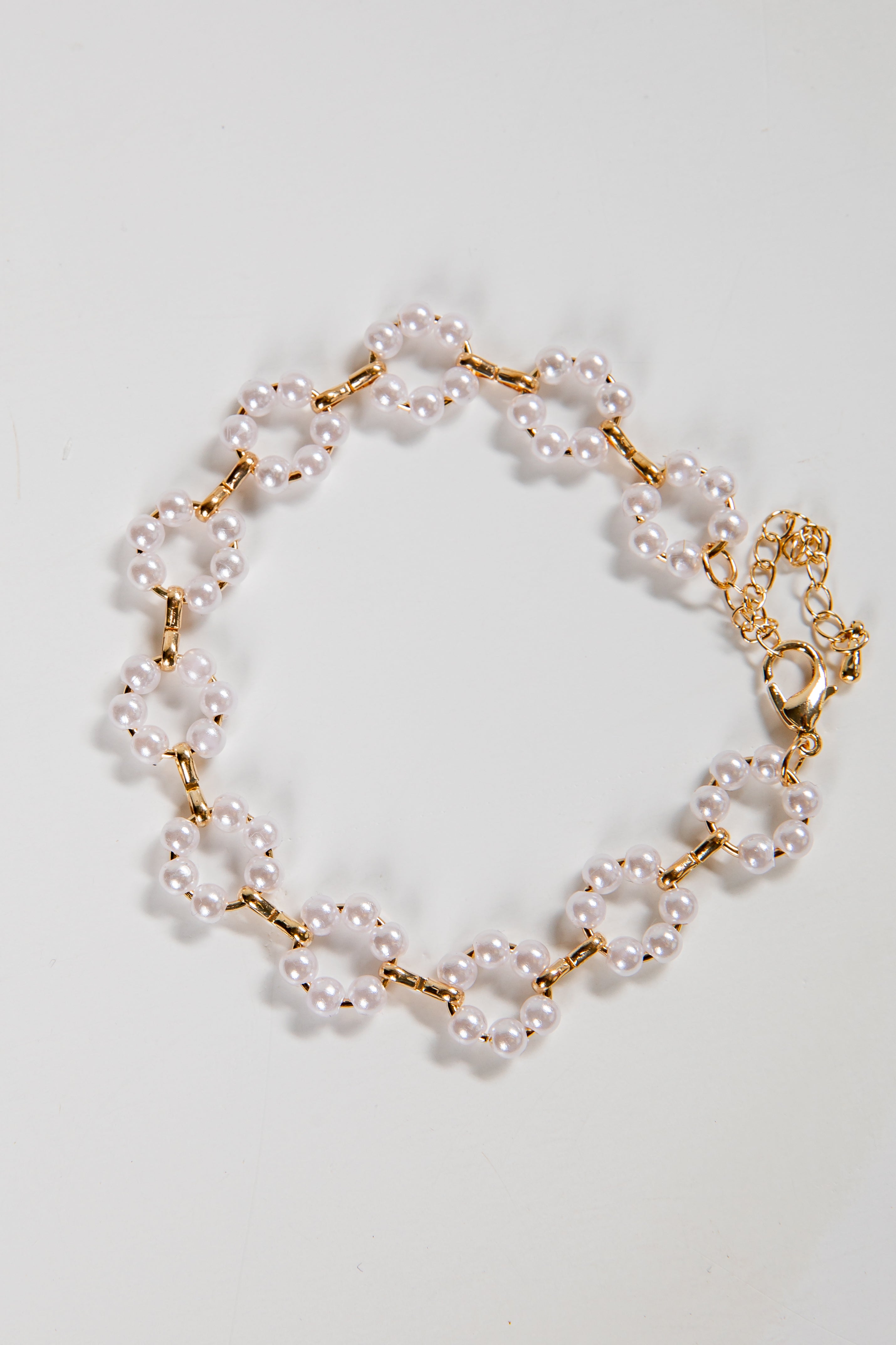 Pearl bracelet with gold chain on a light gray background
