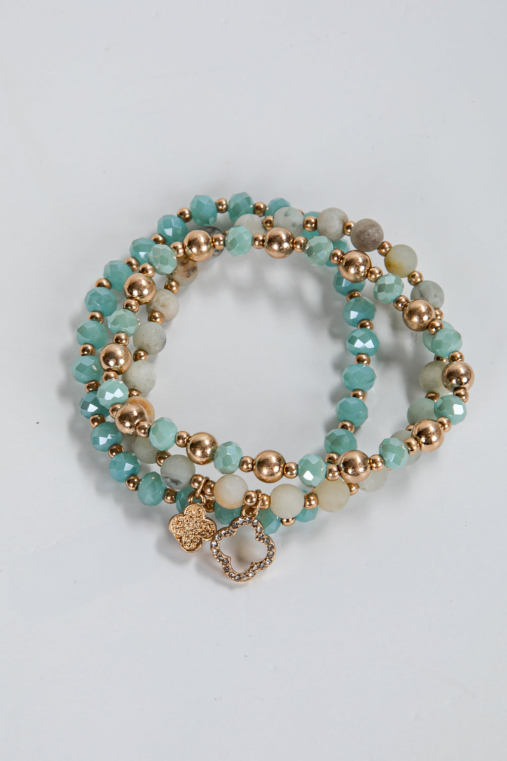 Set of turquoise and gold beaded bracelets on a light gray background
