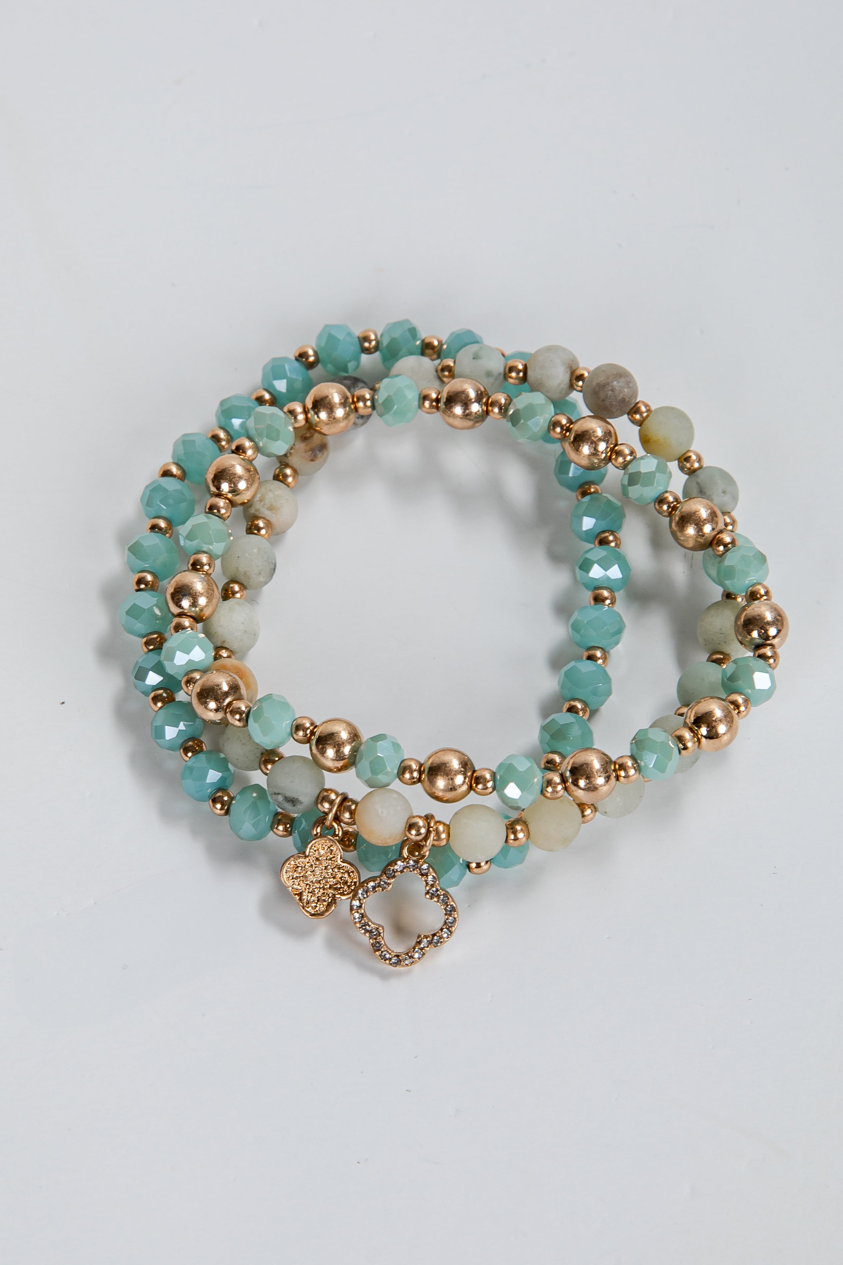 Set of turquoise and gold beaded bracelets on a light gray background