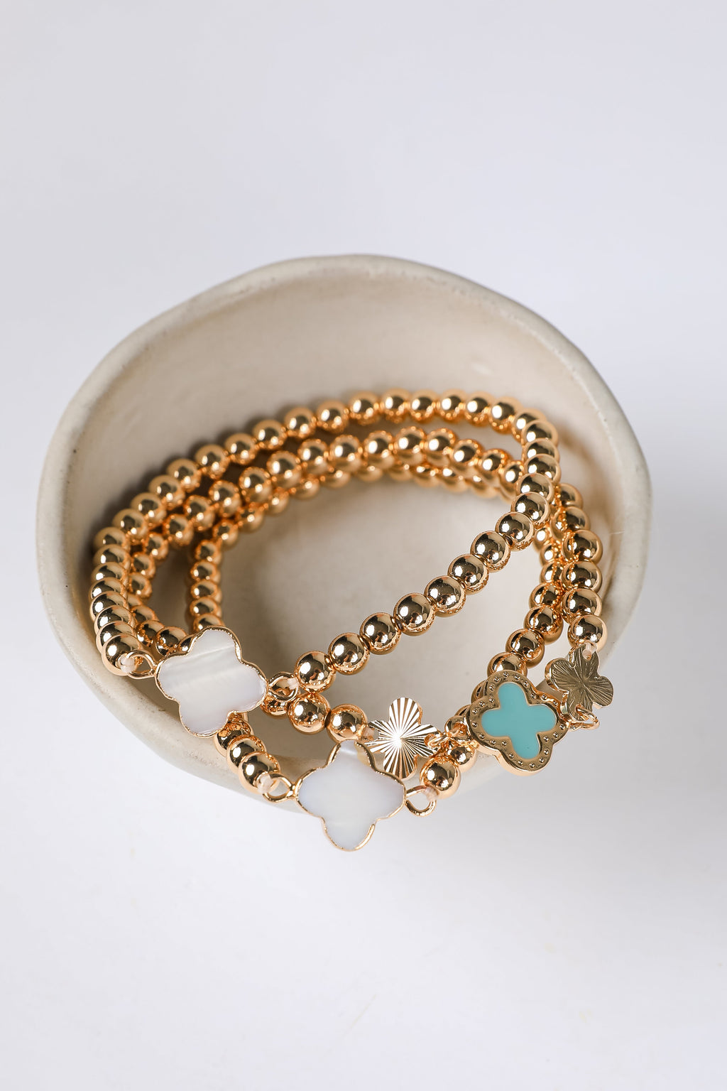 Gold bracelets with charms on a white background