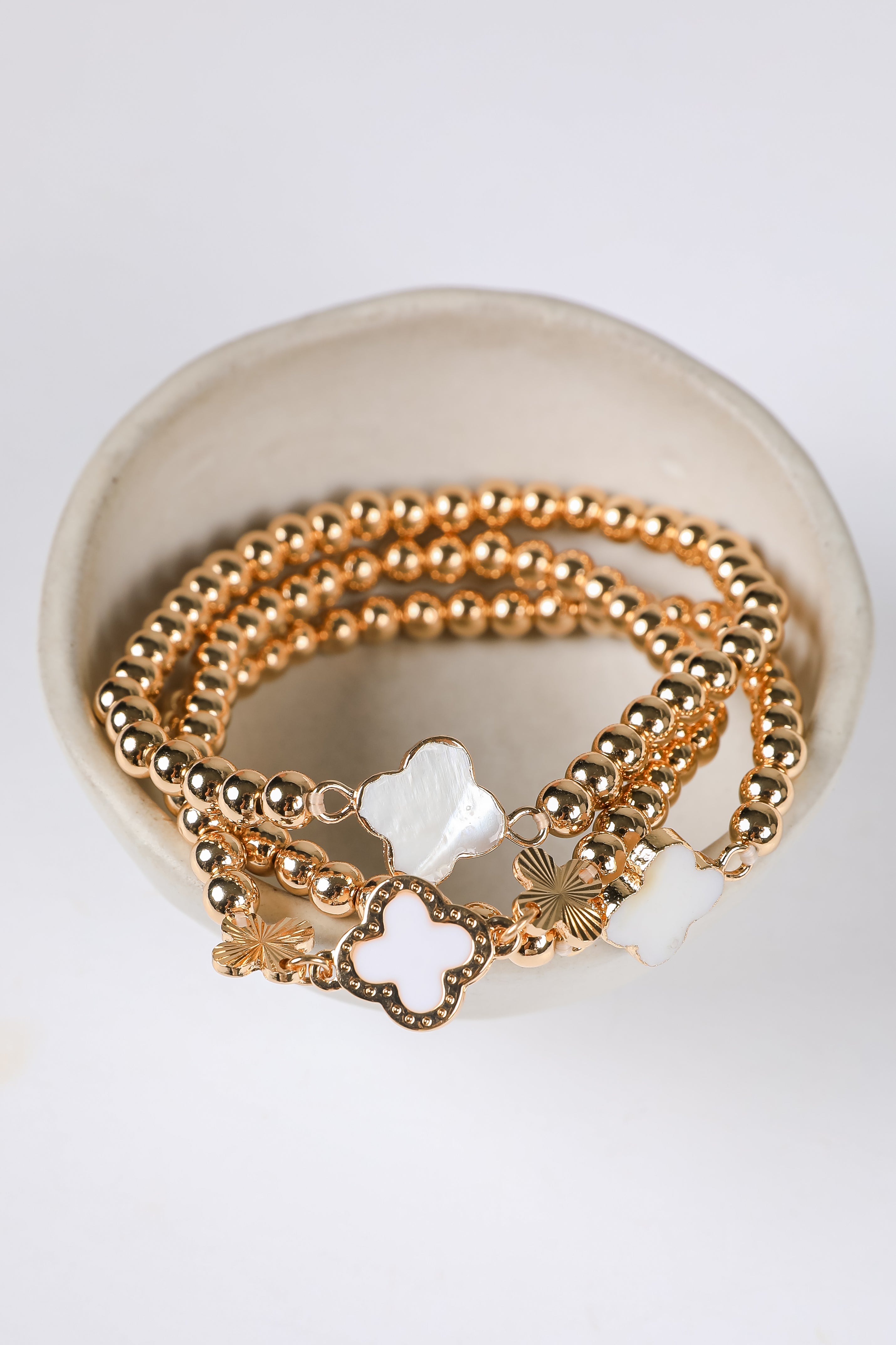 Gold bracelets with star-shaped charms on a white surface